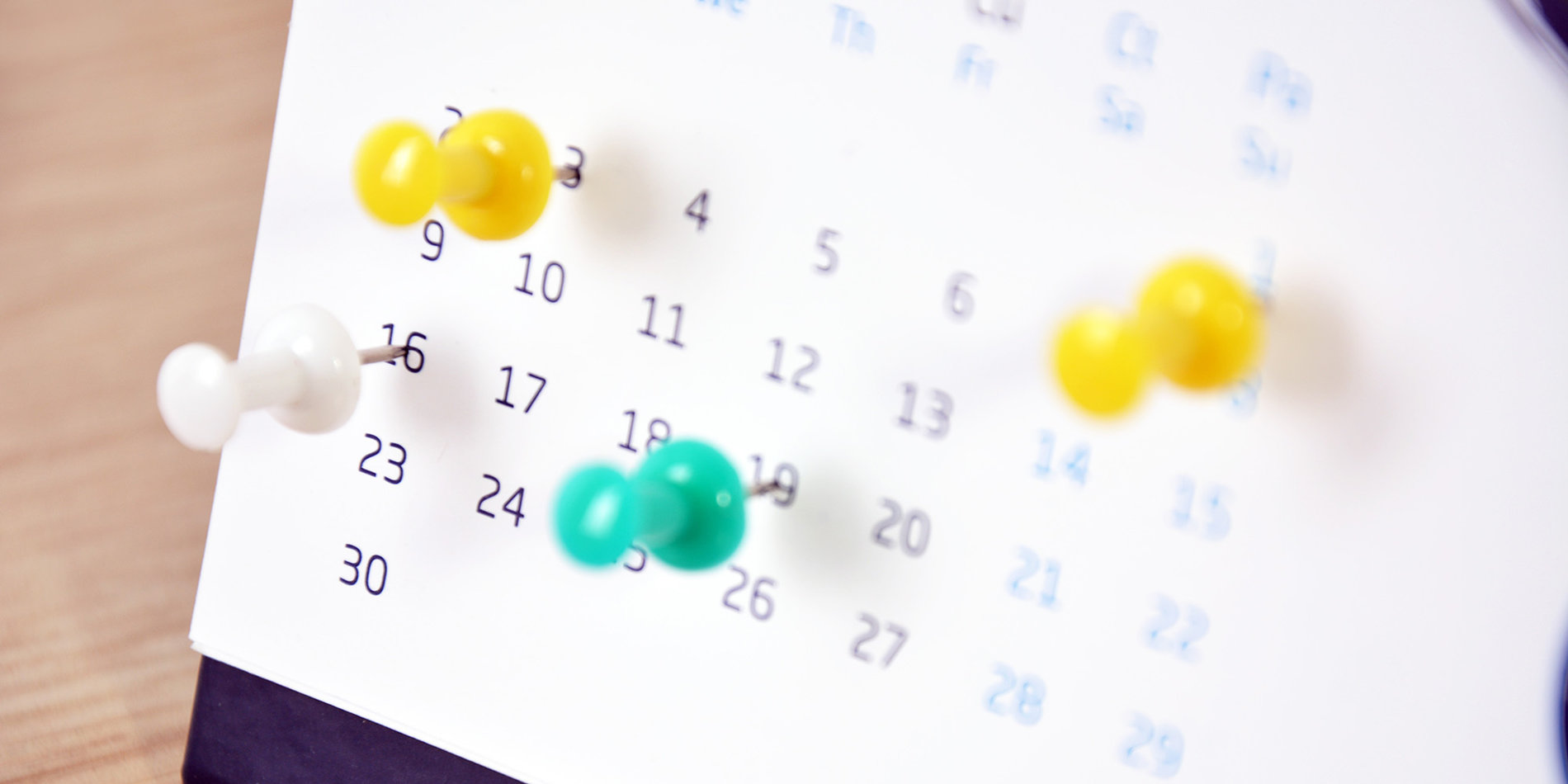 desktop calendar with pushpins on several dates