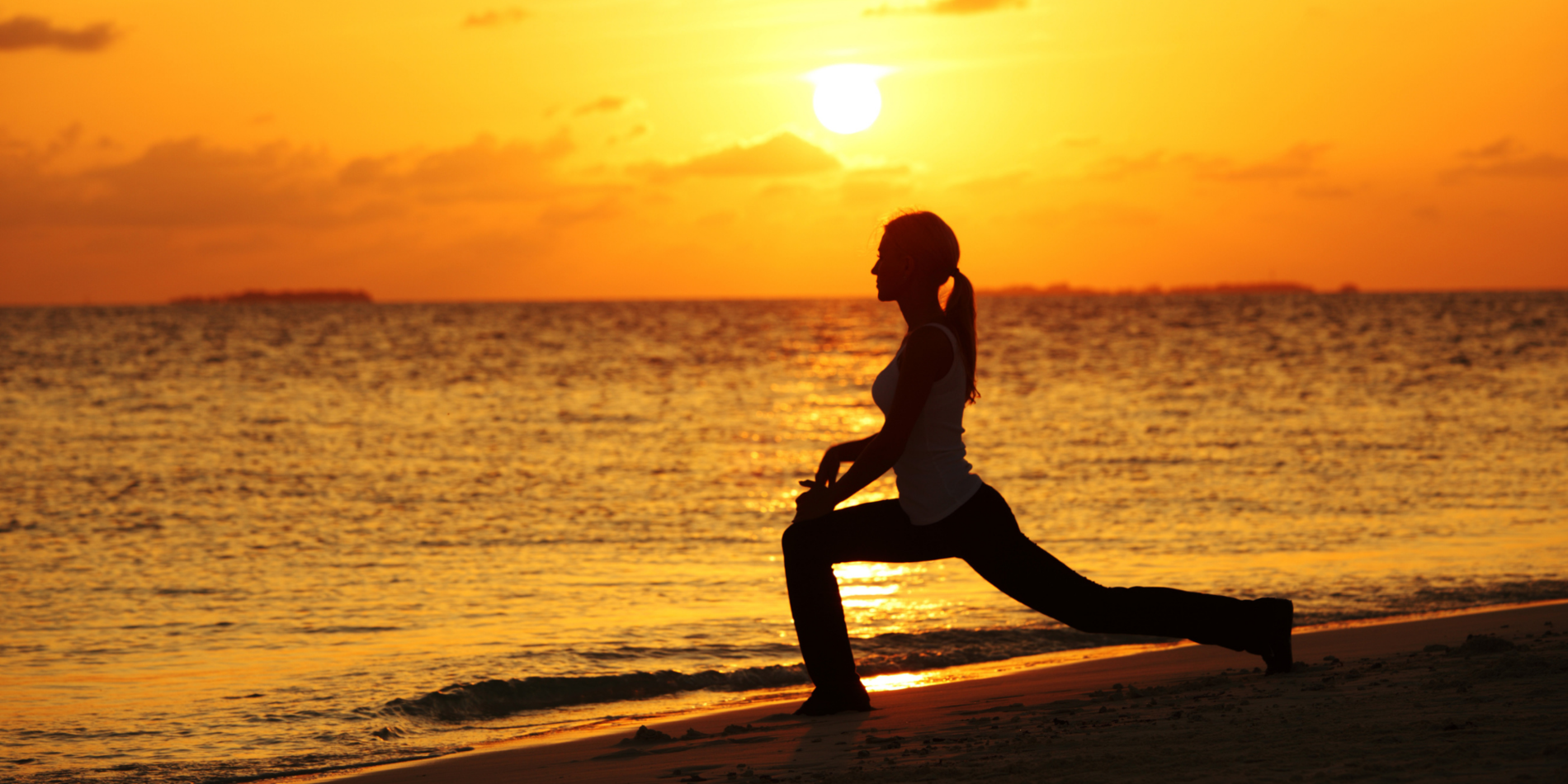 Woman doing yoga on a sunset beach