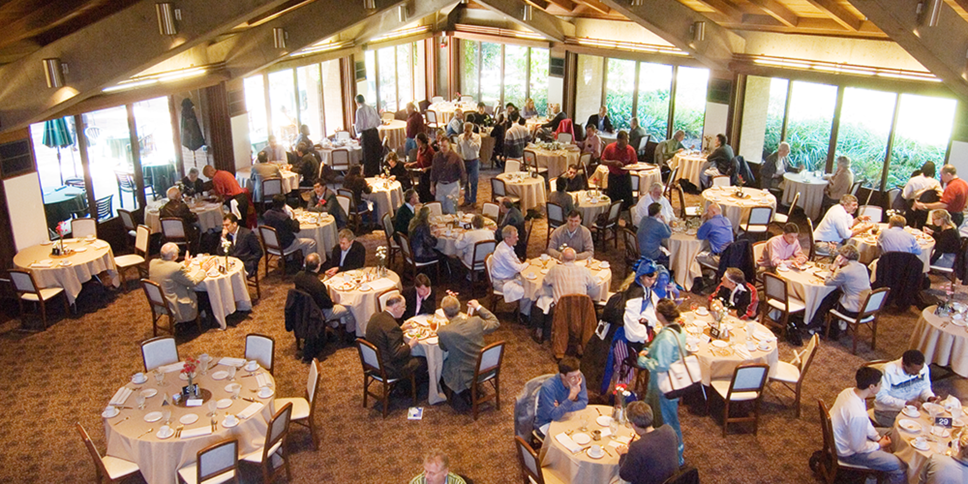 Wide angle view of the Faculty Club interior, with a big gathering of people enjoying a banquet.