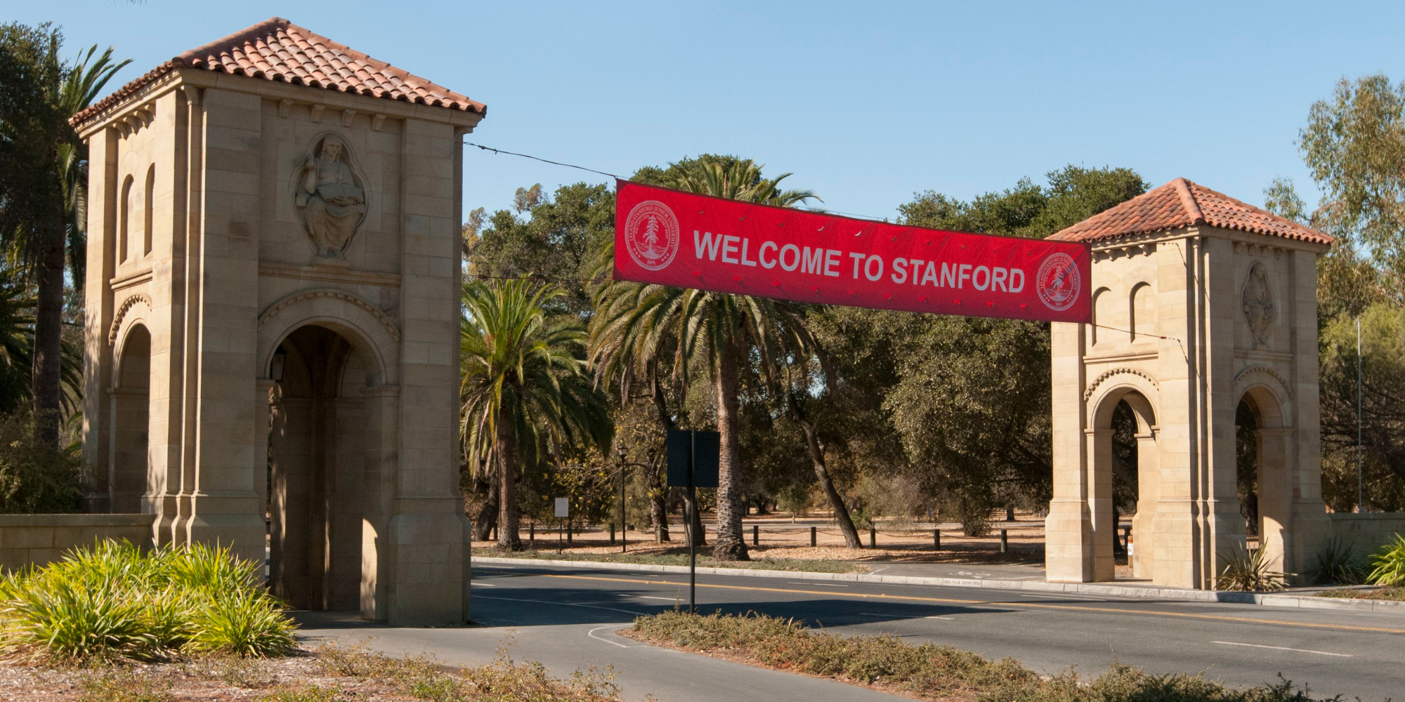 "welcome to stanford" red banner hanging across two pillars on Stanford campus